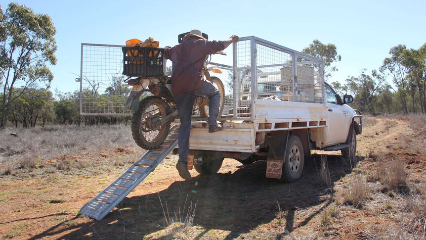 Don Sallway removes his motorbike from the back of his ute.