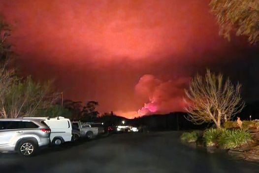 A distant bushfire lights up a red night sky