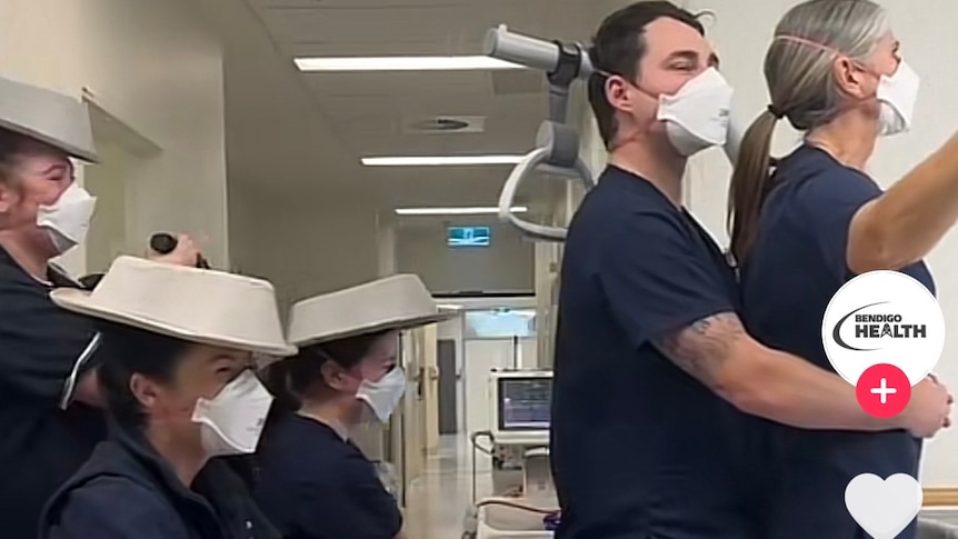 Five hospital workers in nurses uniforms reenact an iconic scene from the movie Titanic