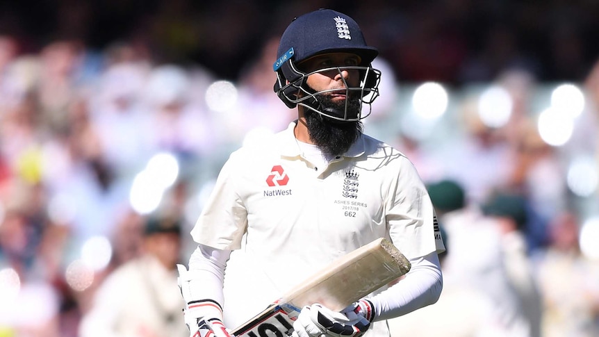 England's Moeen Ali in helmet and holding a cricket bat walks from the pitch