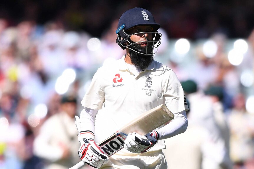England's Moeen Ali in helmet and holding a cricket bat walks from the pitch