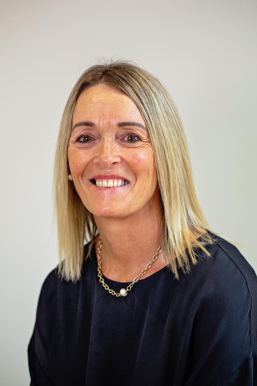 Una mujer con el pelo largo y liso y rubio sonríe.