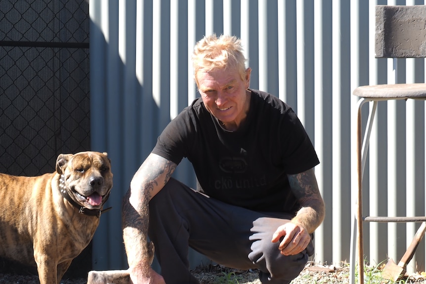 A man crouches with two pet dogs