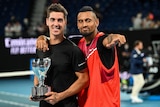 Nick Kyrgios points and puts his other hand around Thanasi Kokkinakis who is holding the Australian Open men's doubles trophy.