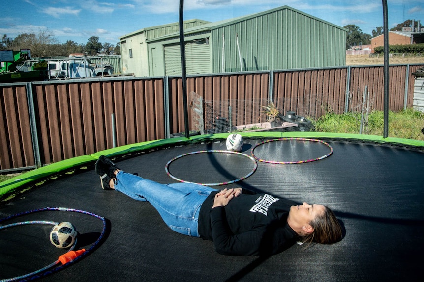Mel Habib lies in the sun on a kids trampoline in her backyard in Liverpool.