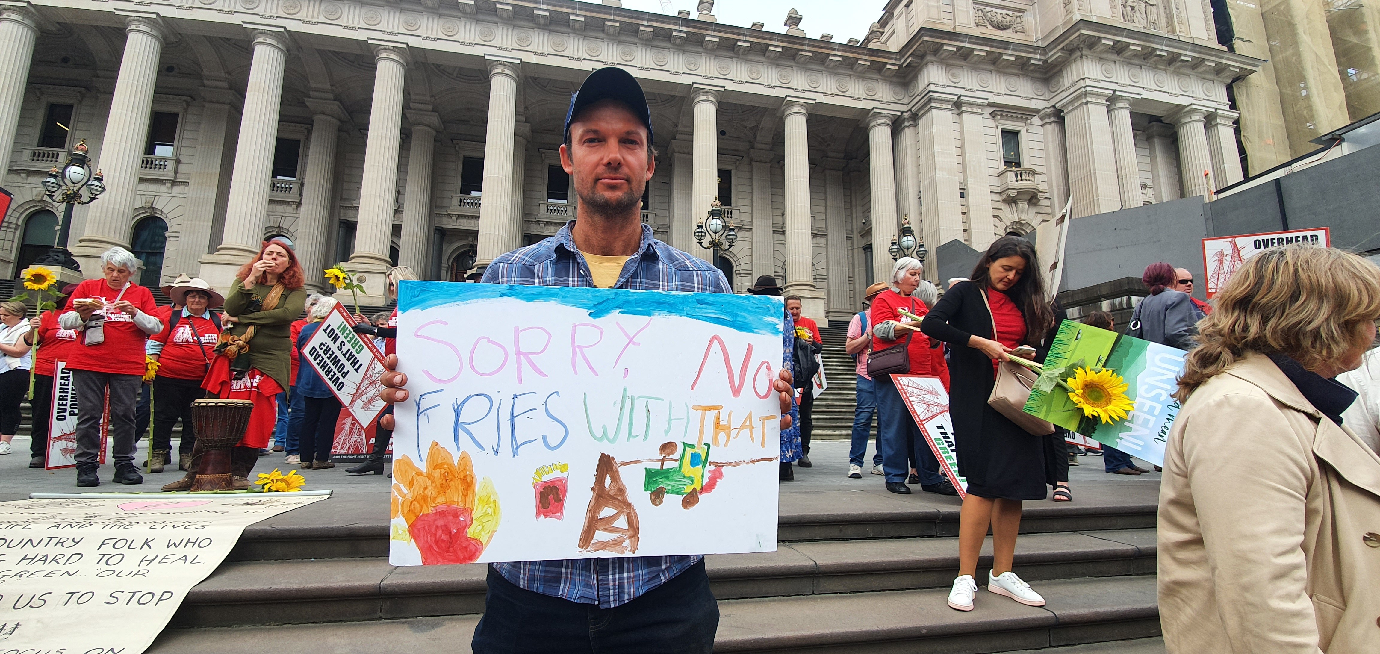 A man holds up a protest sign outside parliament in Melbourne.
