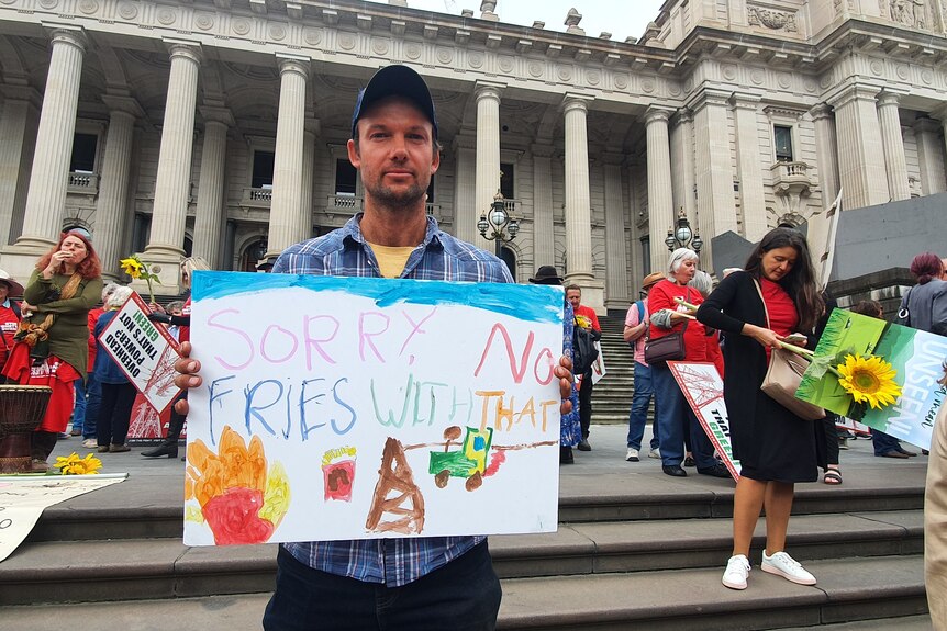 A man holds up a protest sign outside parliament in Melbourne.