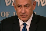 Israeli Prime Minister Benjamin Netanyahu delivers a speech in front of a blue background