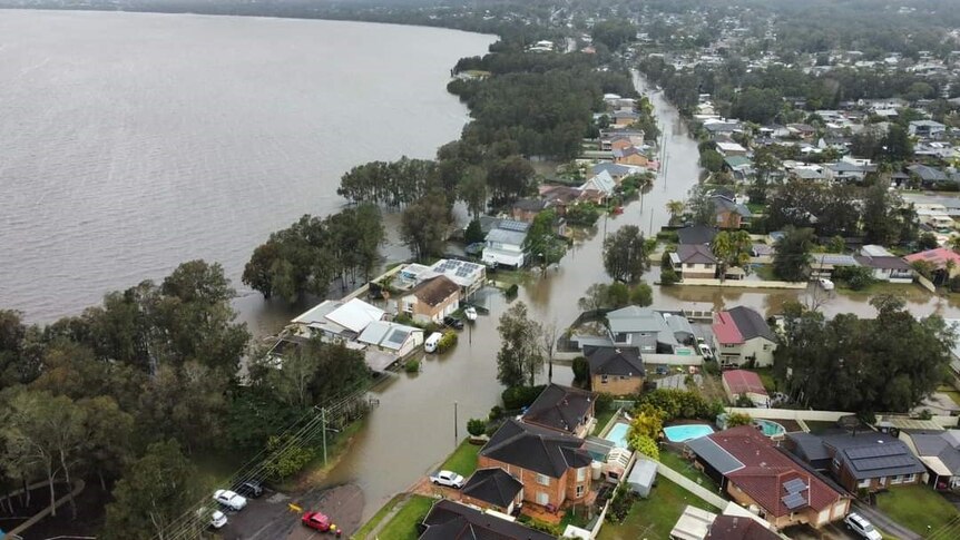 Drone vision of flooded residential streets next to large lake 