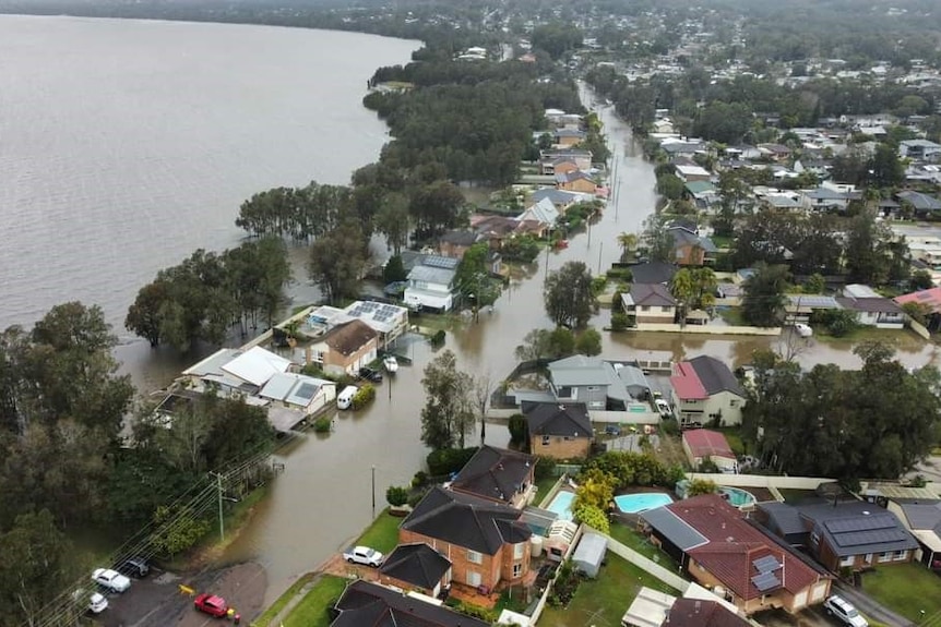 Drone vision of flooded residential streets next to large lake 