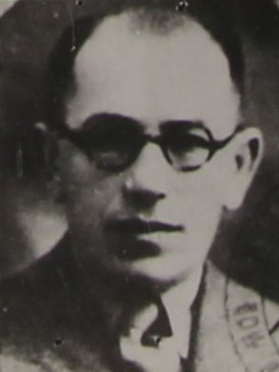 Blurry black and white photo of a balding man wearing spectacles.