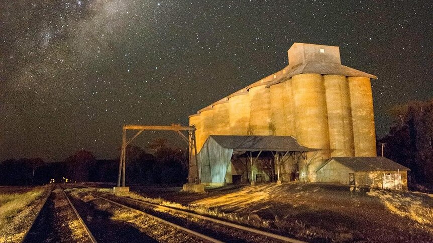 Silos photographed at night below a starry sky.