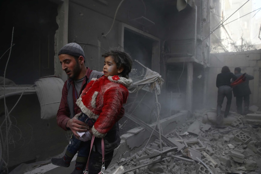 A man carries a child through rubble.