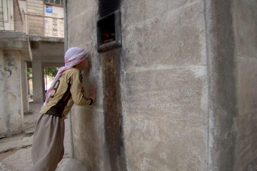 Boy kisses the stone wall of the Yazidi temple