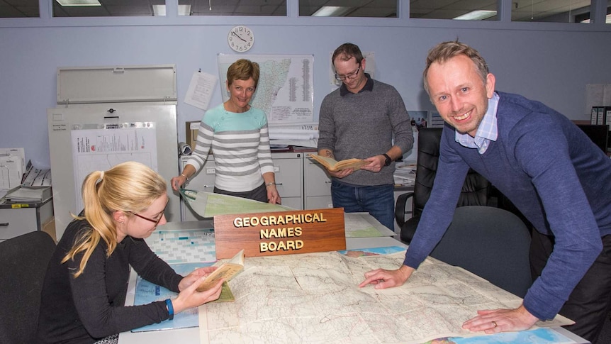 Four people standing around a table looking at maps