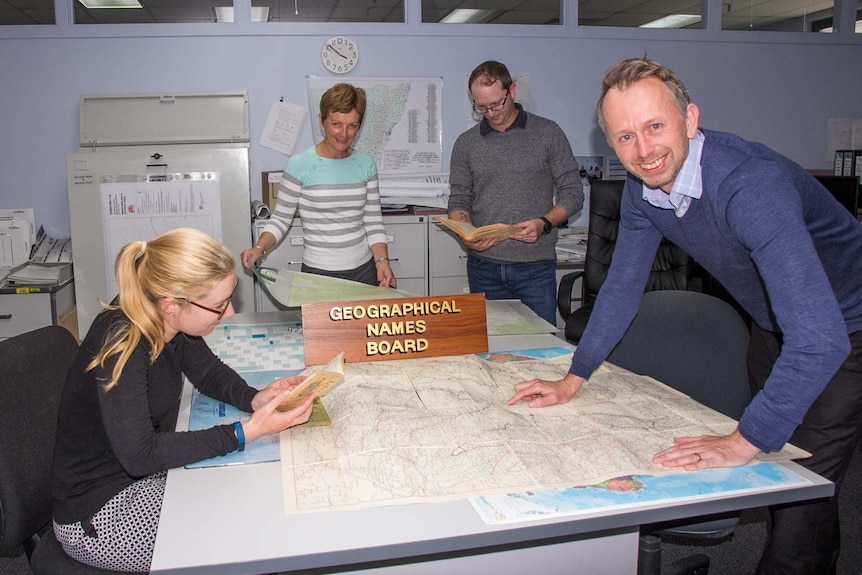 Four people standing around a table looking at maps
