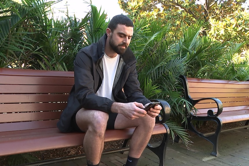 a man sitting on a seat while looking at his mobile phone