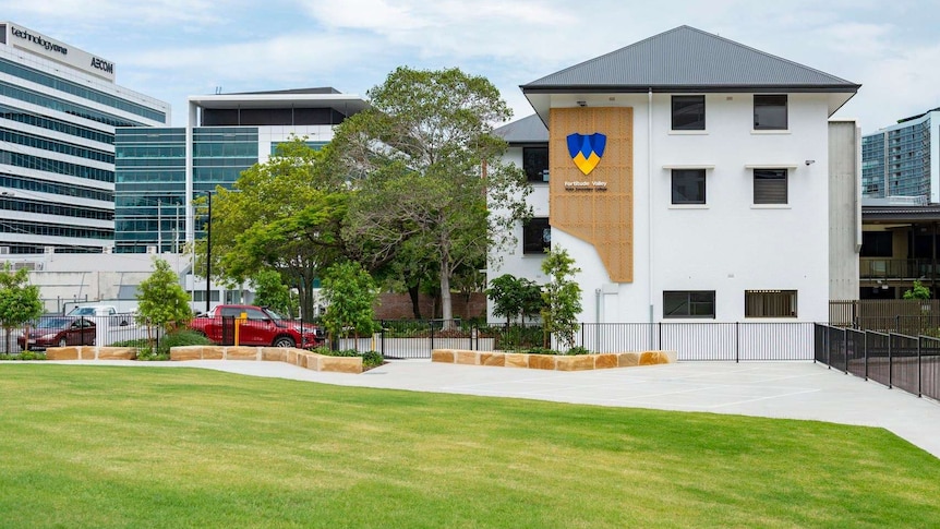 An image of a white building reading Fortitude Valley State Secondary college behind trees