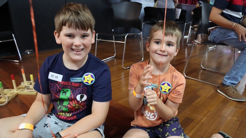 two young boys smiling and sitting on a floor