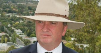 Barnaby Joyce wears an Akubra and speaks into a number of microphones in front of him.