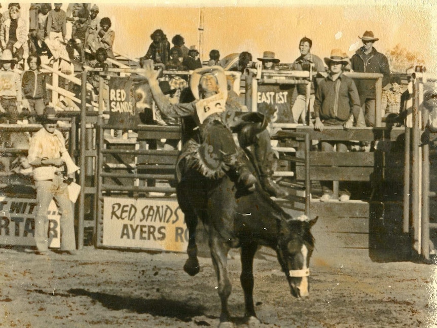 Black and white photo of man riding a bronc at a rodeo in Alice Springs in the 1980s