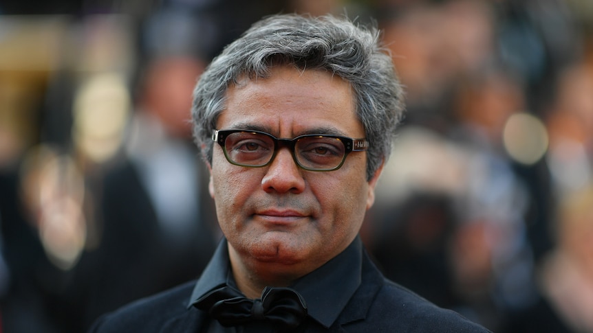 47-year-old Iranian man with greying short hair wearing black shirt and jacket and spectacles, head and shoulders only.