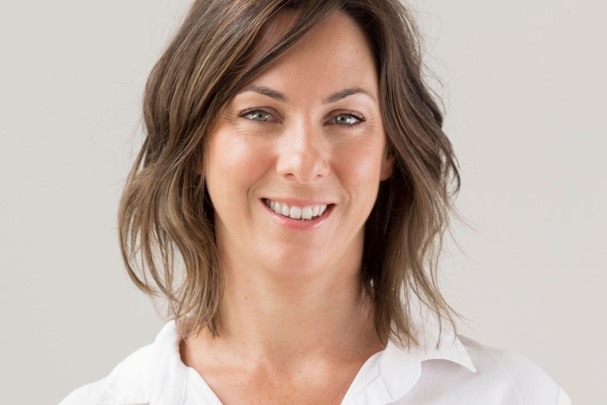 Head and shoulders image of a brunette woman in a white collared shirt. 