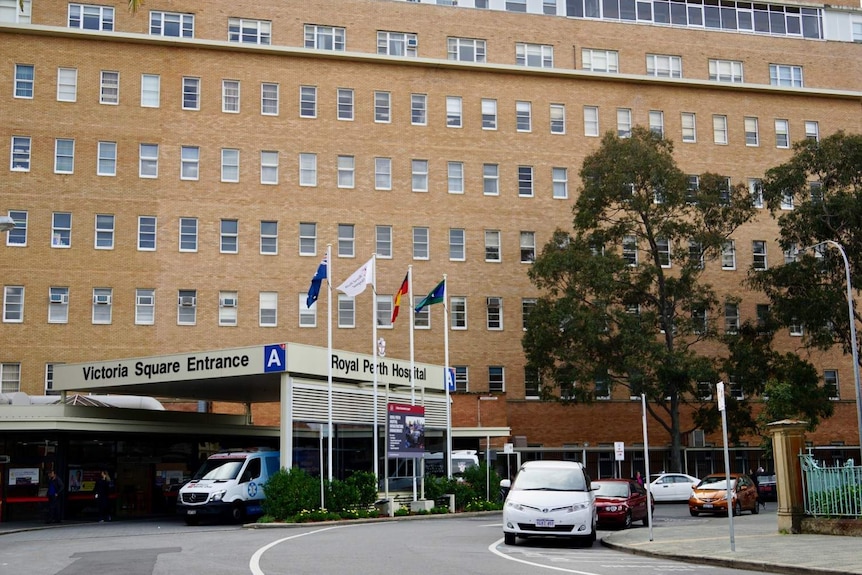 The front of Royal Perth Hospital with an ambulance bay and flags.