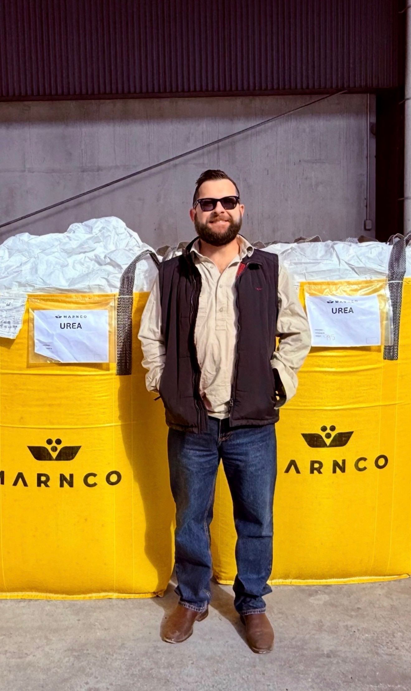A man stands in front of yellow bags filled with urea