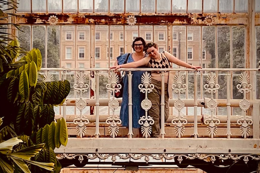 A woman and teenage girl pose for a photo on a balcony.