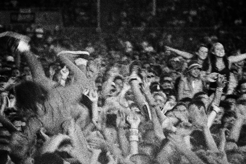 People crowd surf among a sea of hands and heads