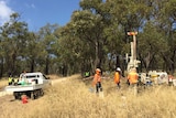 Workers stand around a drill rig in Bibra Lake, near a ute and two police officers.