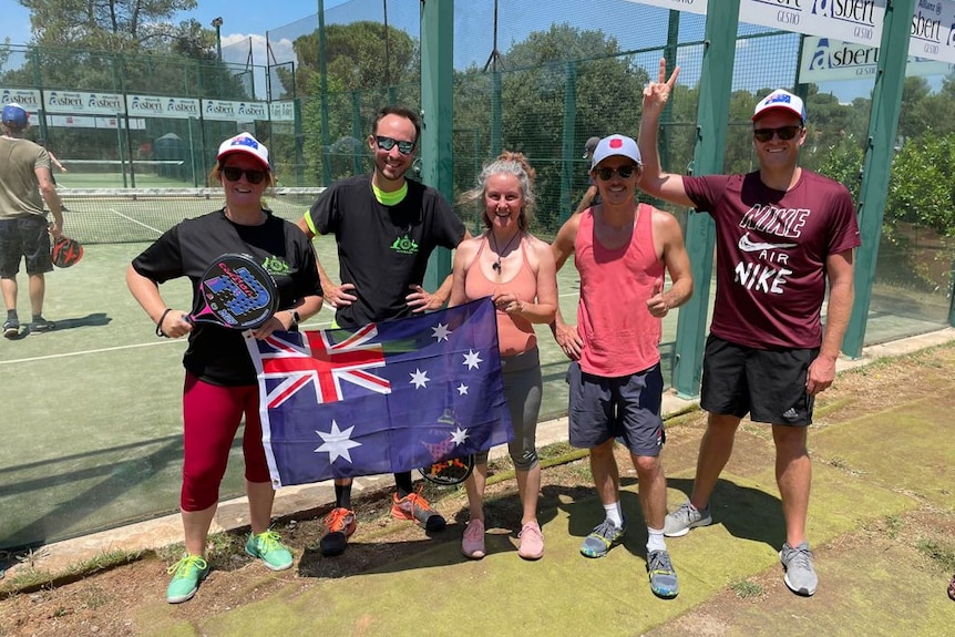 A group of people standing infront of a padel court holding the Australian flag