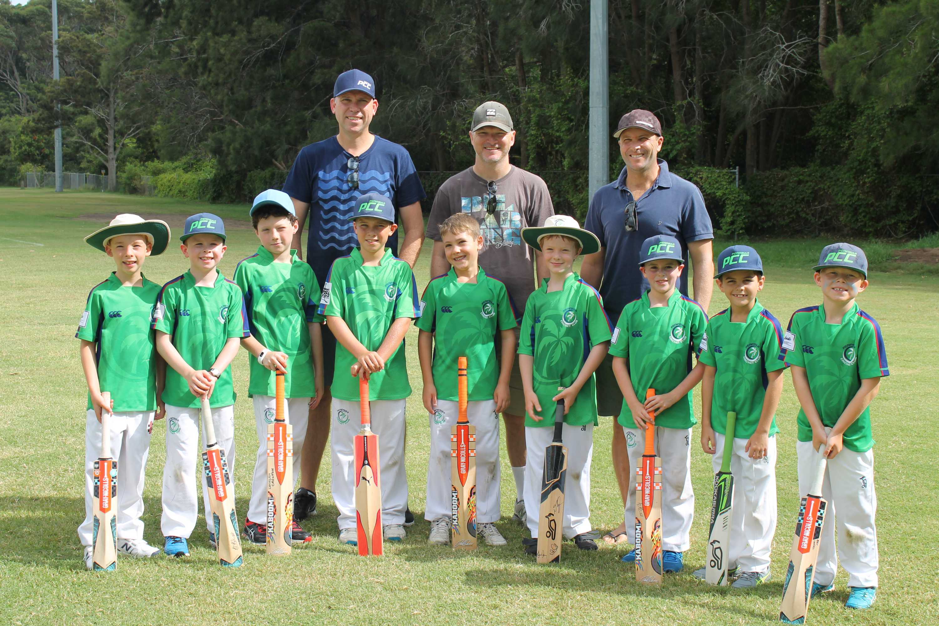 Team photo of young boys in cricket gear with their dads