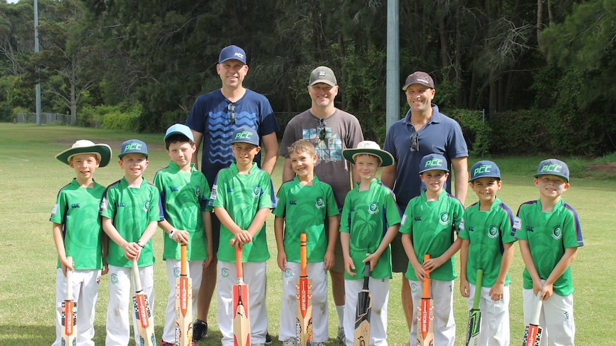 Team photo of young boys in cricket gear with their dads