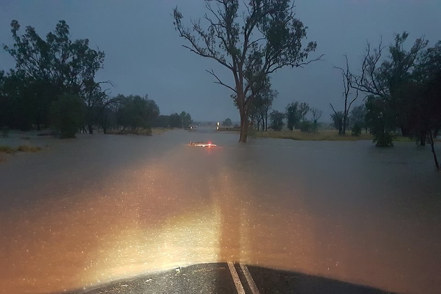 A car submerged to its roof on a flooded road.