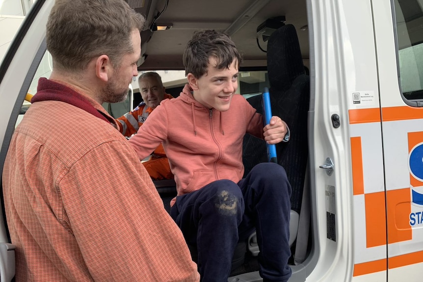 A smiling boy gets out of an SES truck