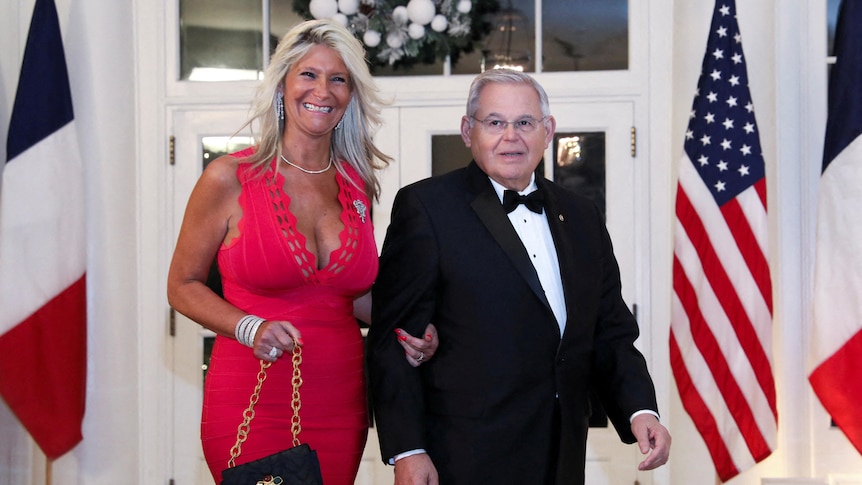 Nadine and Bob Menendez stand in a room with French and American flags next to them.