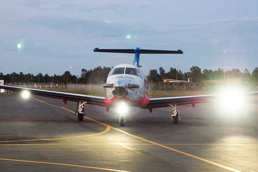 A head-on shot of an RFDS plane on a runway with its lights on.