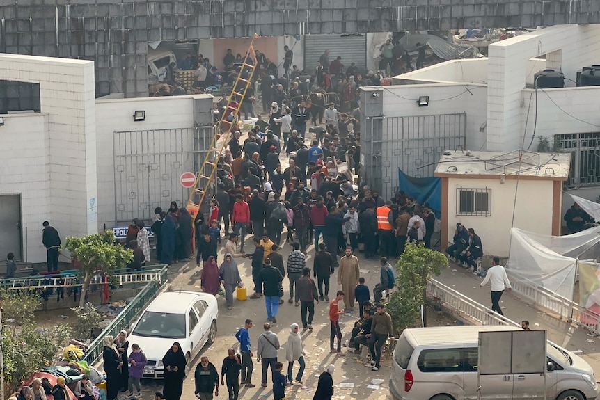 at the hospital gate, hundreds of people walk in and out of the hospital compound
