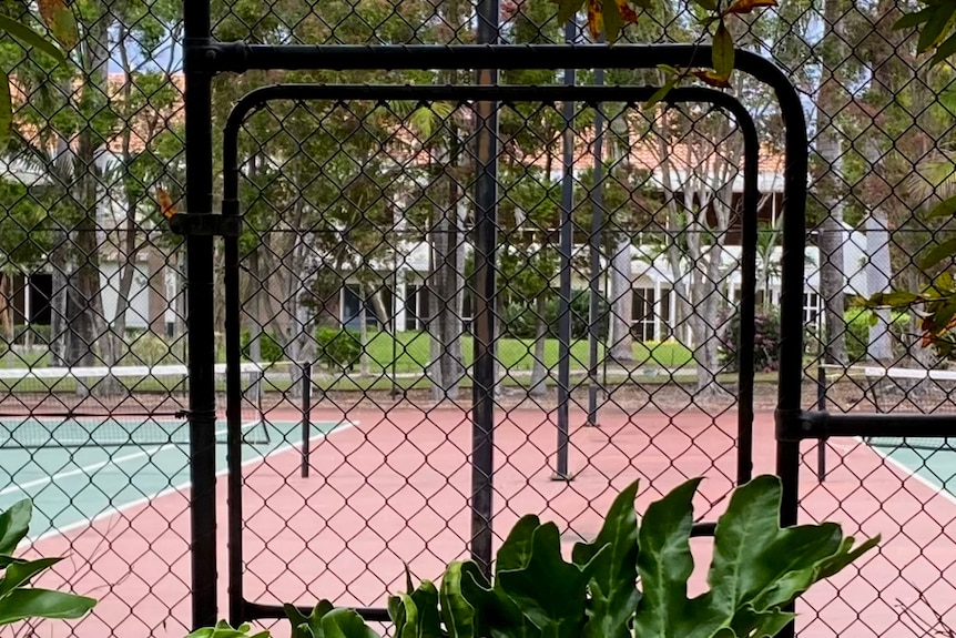 a tennis court behind a black chain mesh fence 