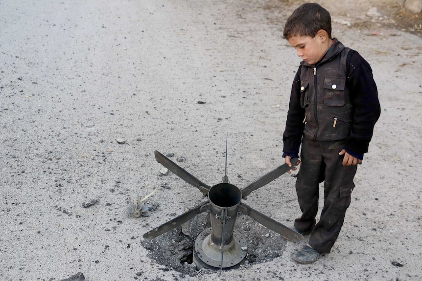 A boy touches a bomb in Syria