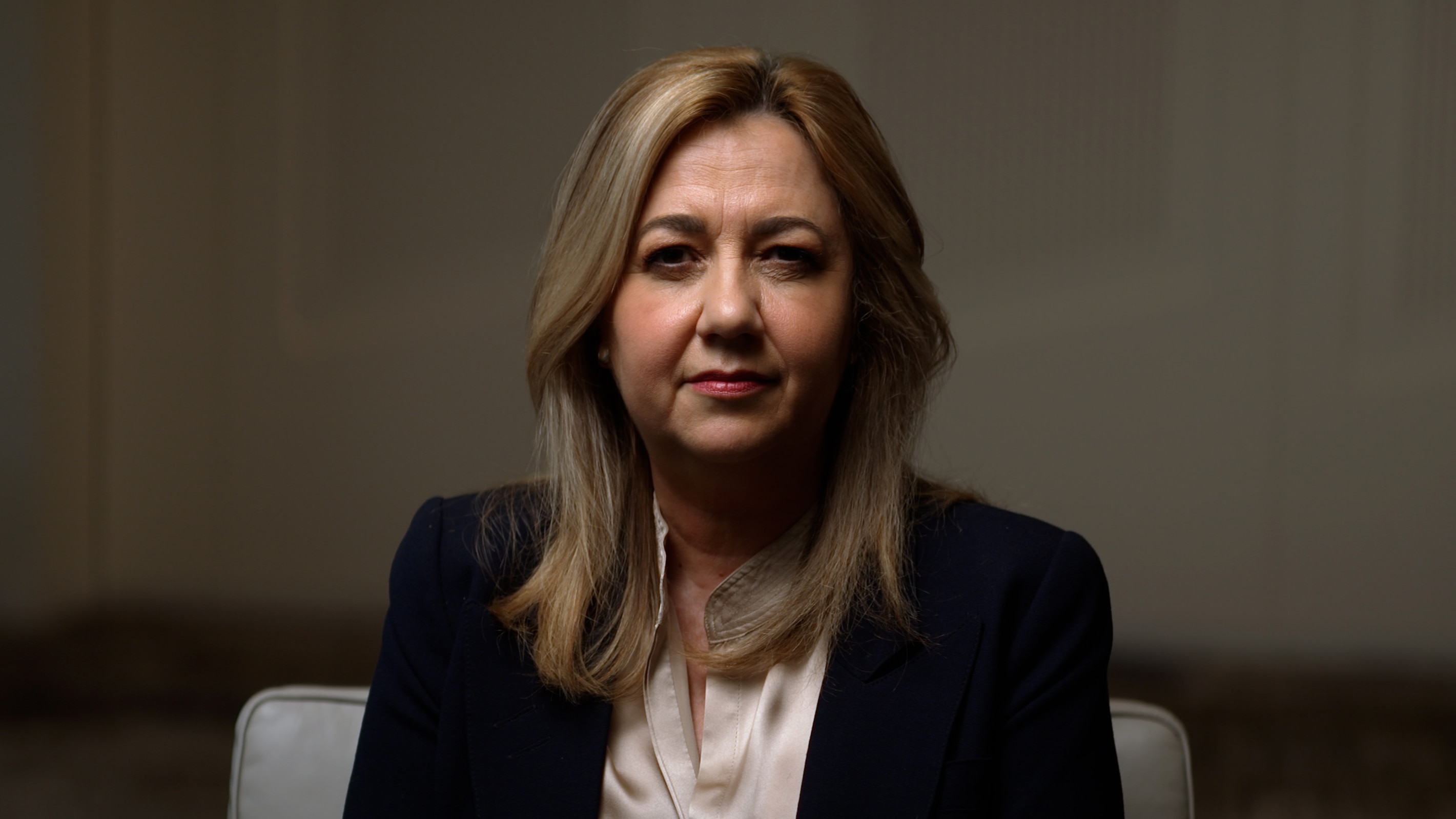 Annastacia Palaszczuk sits in a chair, looking directly into camera with a serious facial expression.
