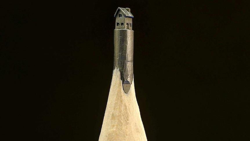 Close up view of a sculpture of a two-storey house made in the tip of a pencil.