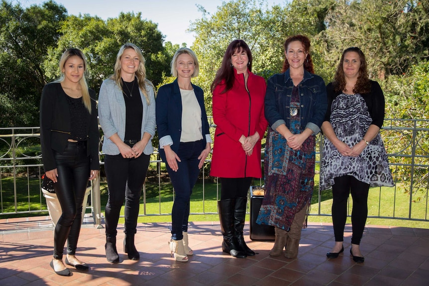 Women stand on a balcony.