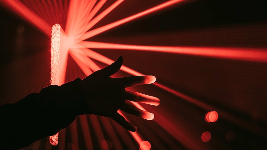 Picture of a hand with red laser lights behind it