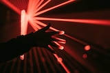 Picture of a hand with red laser lights behind it