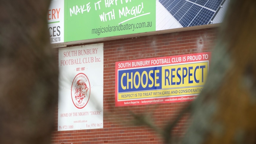 Two signs, including one that reads "choose respect",  hang on a red brick wall.
