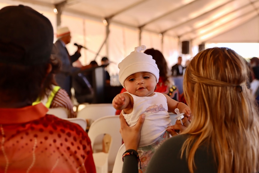 Un bebé es sostenido durante la ceremonia.