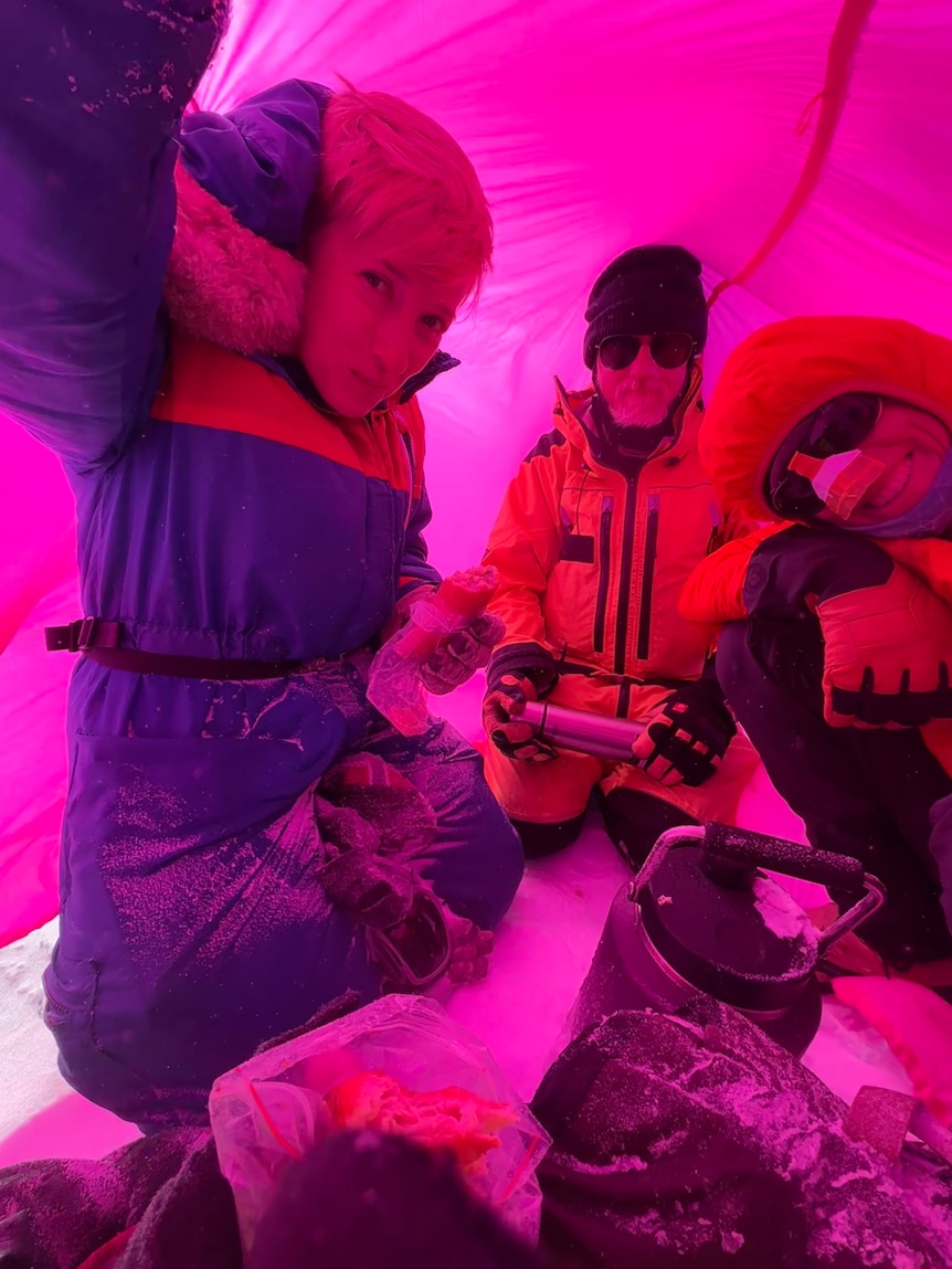 Kate Selway with colleagues sheltering on a glacier in a 'survival' bag